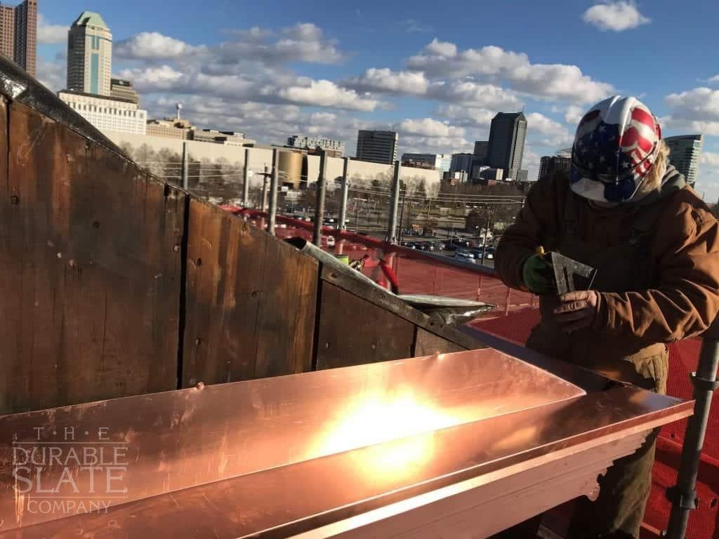 durable slate employee measuring a piece of copper