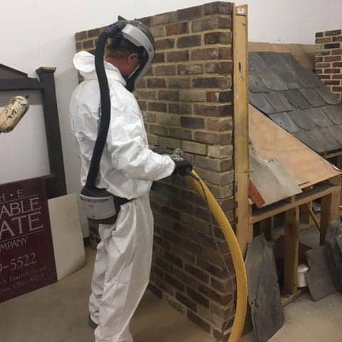 durable slate employee learning the correct way to saw through antique masonry in a full hazmat suit
