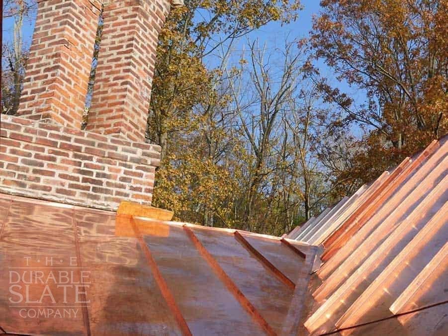 cincinnati copper standing seam roof with fall foliage and chimney in the background